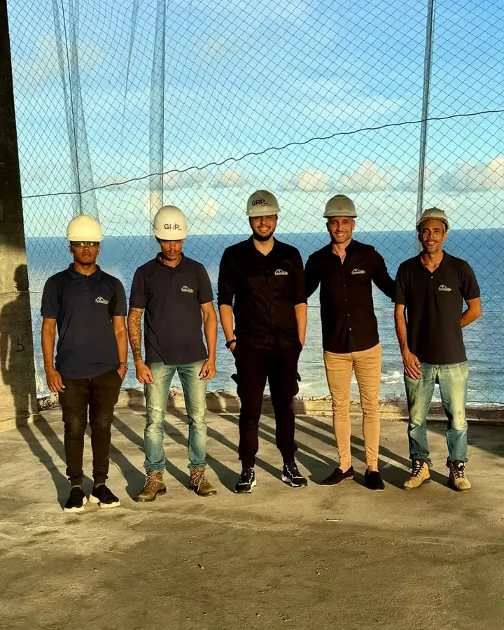 Equipe HomeLife de capacete em obra de frente para o mar